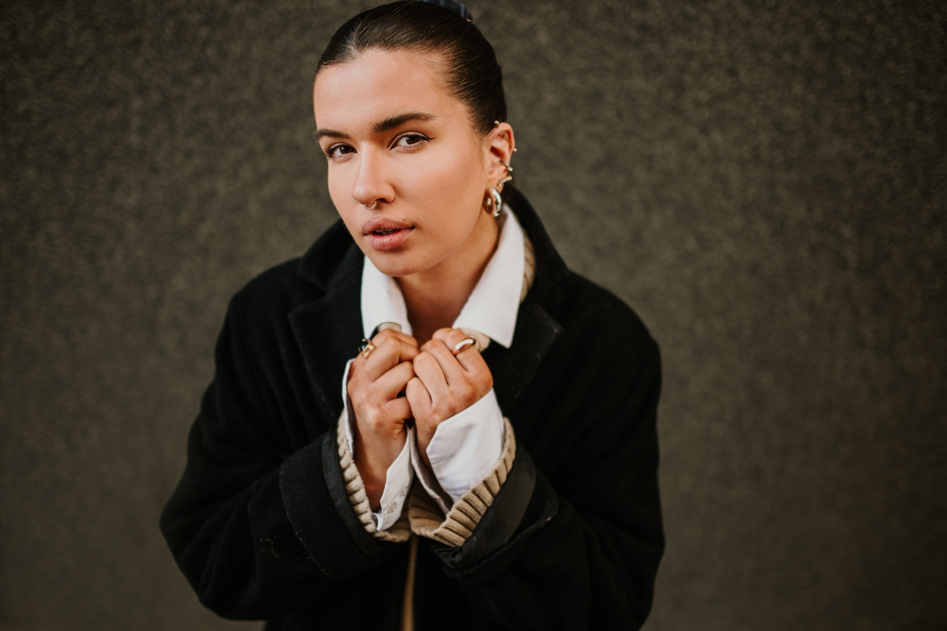 Young attractive fashionable woman in coat on street looking at camera